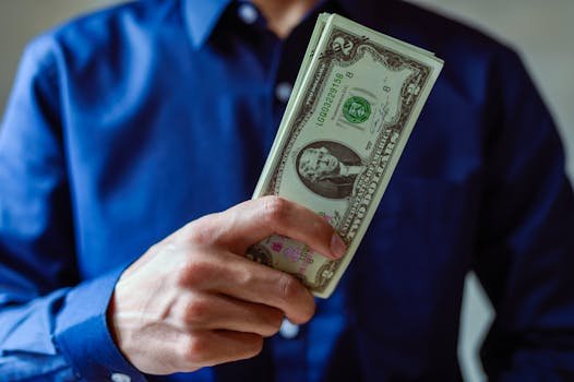 Close-up of a person holding two dollar bills, representing wealth and finance.